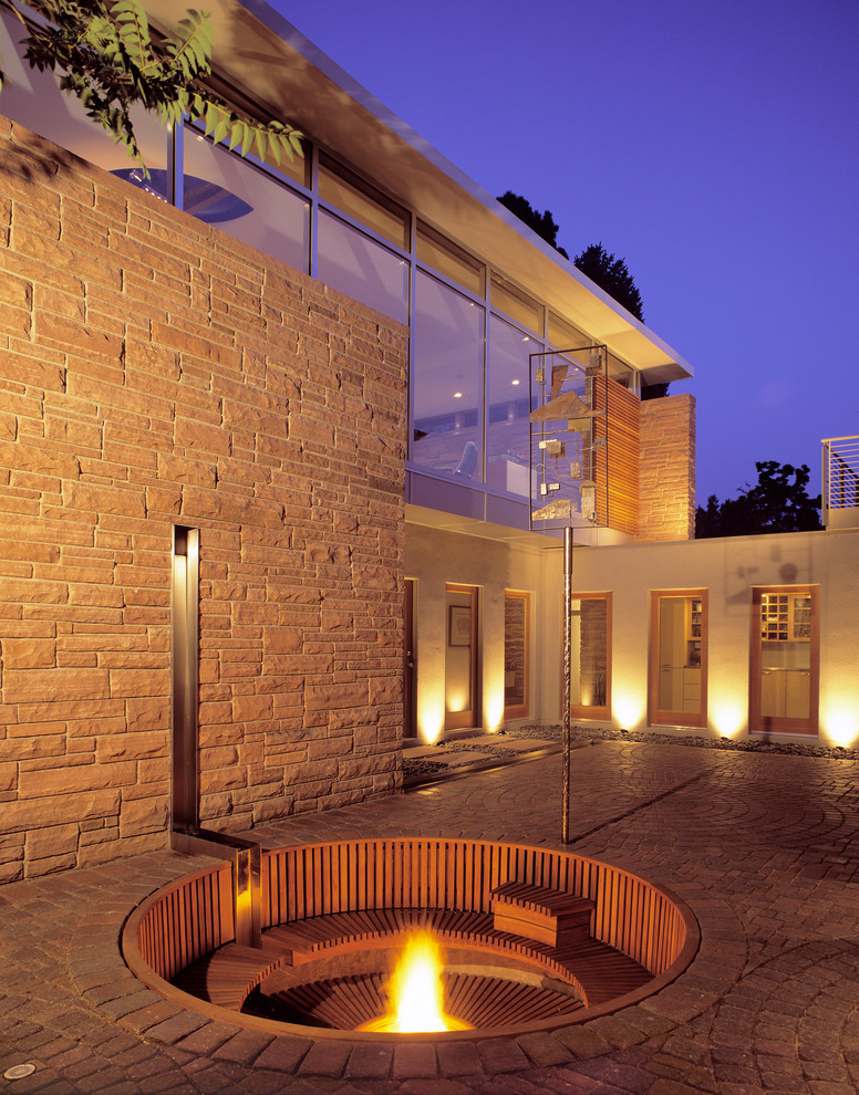 Cette image montre une terrasse design avec une cour et un foyer extérieur.