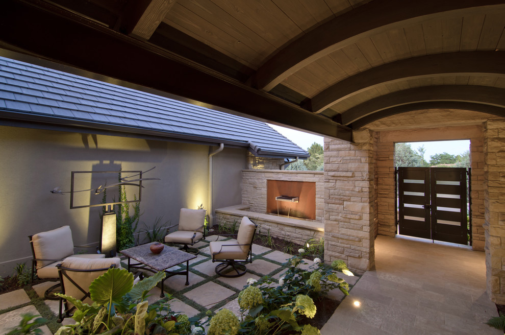 Immagine di un patio o portico eclettico di medie dimensioni e in cortile con fontane, pavimentazioni in pietra naturale e un tetto a sbalzo