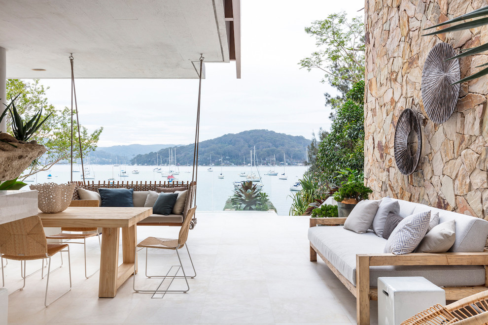 Cette photo montre une terrasse avec des plantes en pots bord de mer avec une dalle de béton et une extension de toiture.