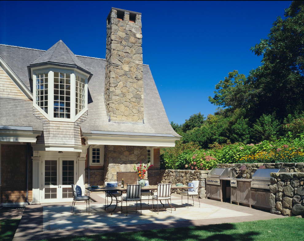 Aménagement d'une terrasse victorienne avec une cuisine d'été, des pavés en pierre naturelle et une extension de toiture.