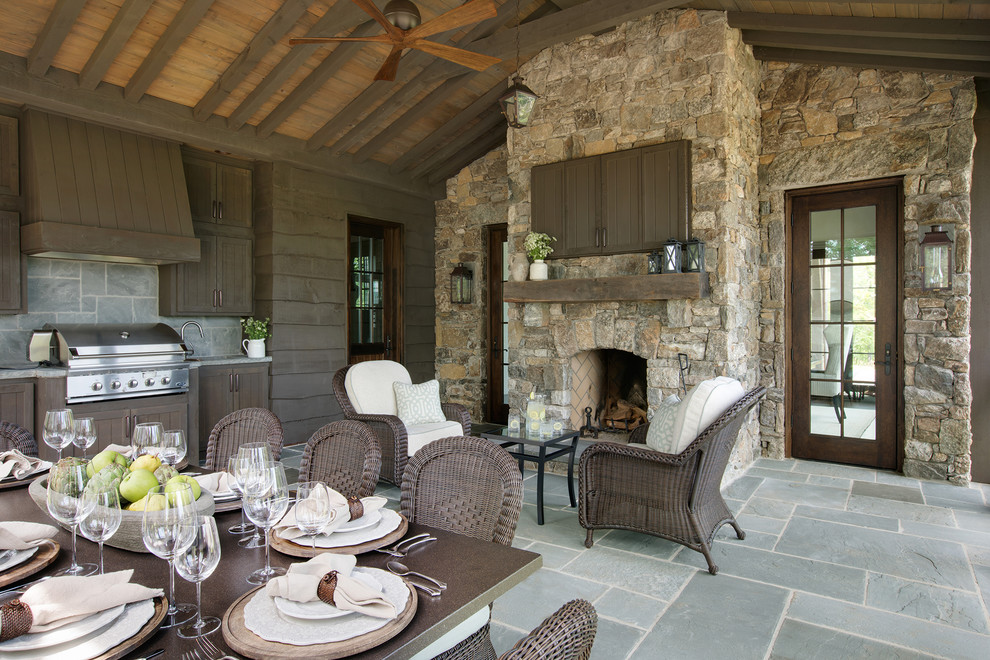 Exemple d'une terrasse arrière chic avec une cuisine d'été, des pavés en pierre naturelle et une extension de toiture.