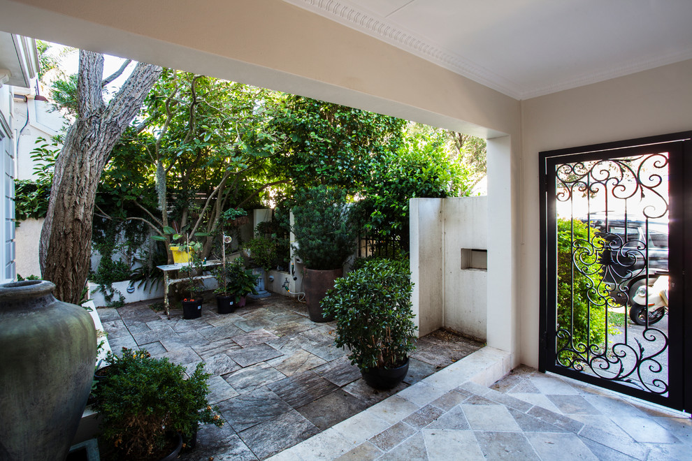 Immagine di un patio o portico design di medie dimensioni e davanti casa con pavimentazioni in pietra naturale e un tetto a sbalzo