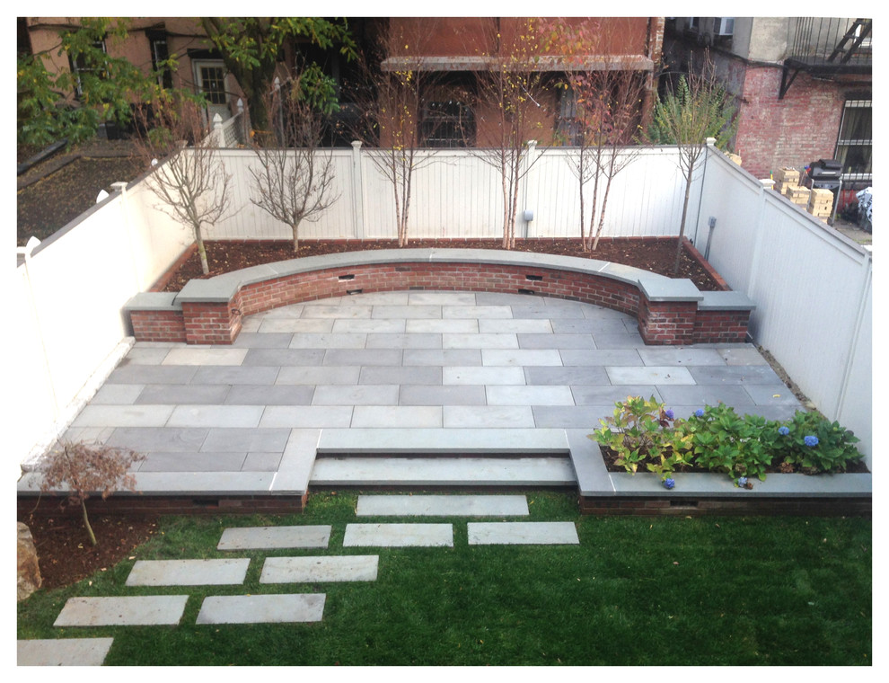 Cette image montre une terrasse arrière minimaliste avec des pavés en béton et aucune couverture.