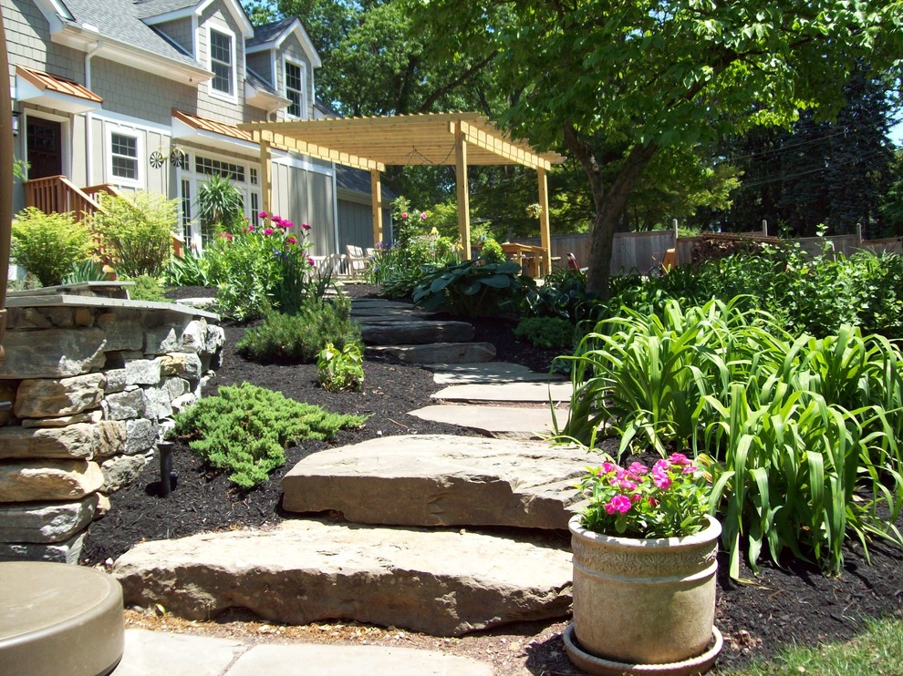 Medium sized country back patio in Philadelphia with a potted garden, natural stone paving and a pergola.