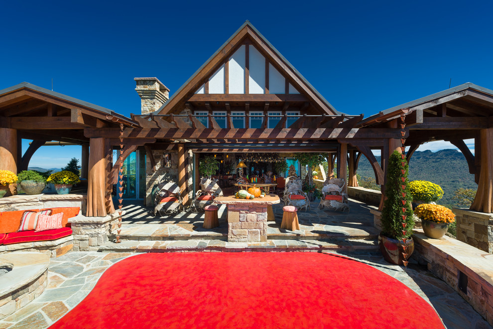 Immagine di un ampio patio o portico stile rurale dietro casa con un focolare, pavimentazioni in pietra naturale e una pergola