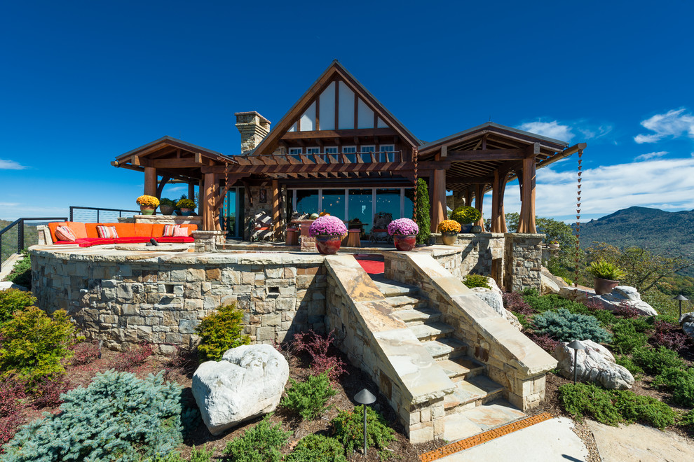 Cette photo montre une très grande terrasse arrière montagne avec un foyer extérieur, des pavés en pierre naturelle et une pergola.