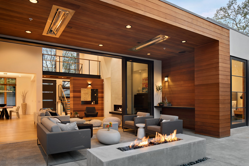 На фото: двор в современном стиле с местом для костра, покрытием из бетонных плит и навесом с
