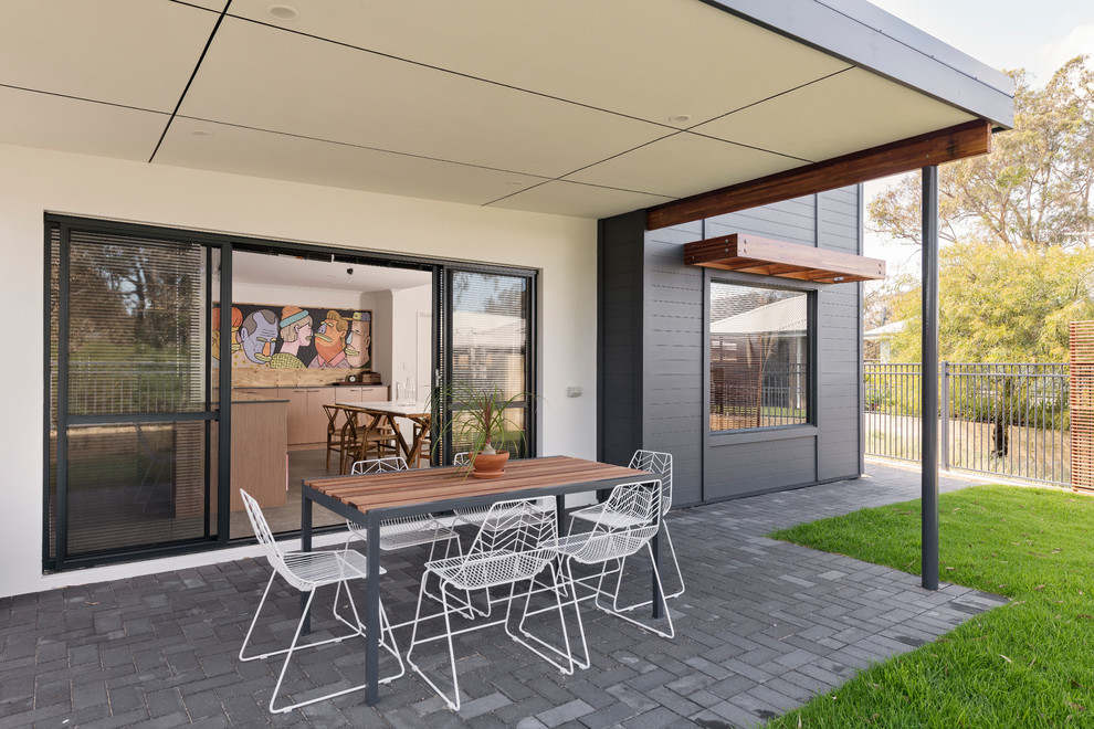 Idee per un patio o portico costiero di medie dimensioni e dietro casa con pavimentazioni in cemento e un tetto a sbalzo