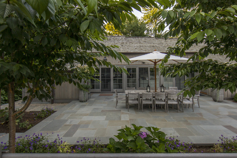 Réalisation d'une terrasse arrière champêtre de taille moyenne avec des pavés en pierre naturelle et aucune couverture.