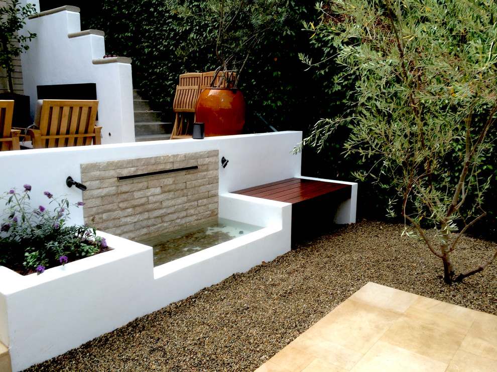 Aménagement d'une terrasse arrière méditerranéenne de taille moyenne avec un point d'eau, aucune couverture et du gravier.