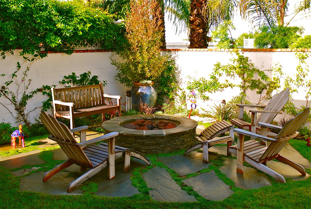 Example of a beach style patio design in Los Angeles with a fire pit and no cover