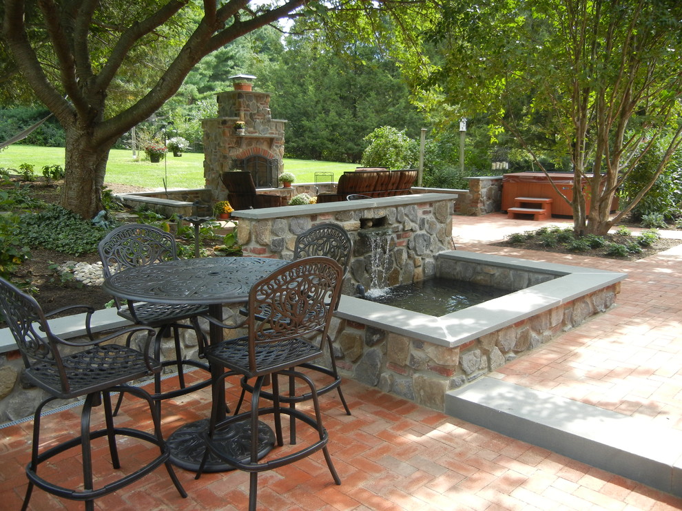 Example of a mid-sized mountain style backyard brick patio design in Philadelphia with a fireplace and no cover