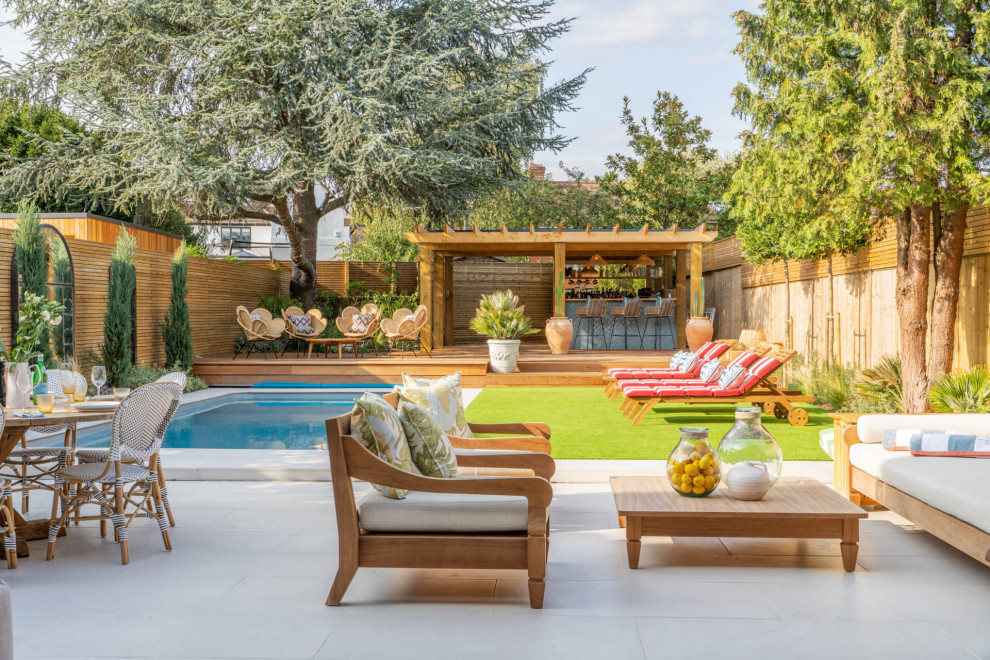 Idee per un patio o portico chic dietro casa con piastrelle e una pergola