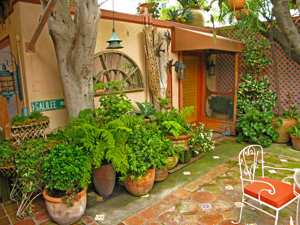 Esempio di un patio o portico eclettico di medie dimensioni e in cortile con un giardino in vaso, piastrelle e nessuna copertura