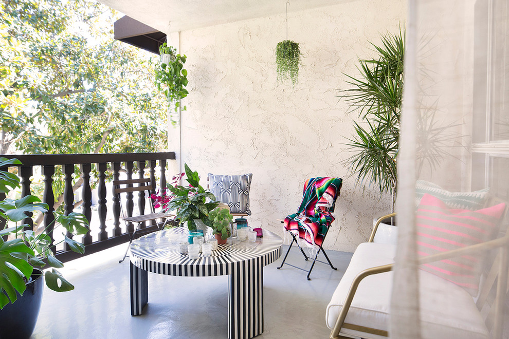 This is an example of a medium sized bohemian back patio in Los Angeles with a roof extension and concrete slabs.