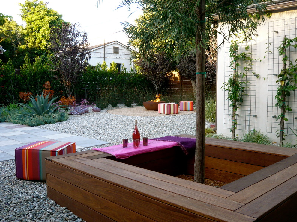 Cette image montre une terrasse arrière design avec un foyer extérieur et des pavés en béton.