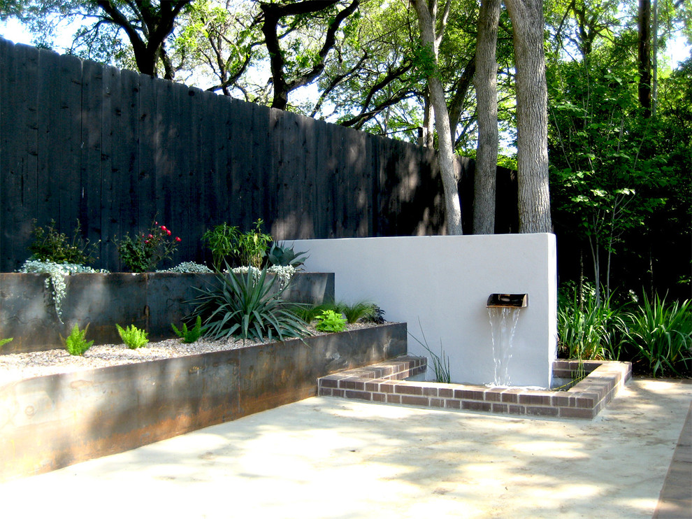 Diseño de patio actual de tamaño medio sin cubierta en patio trasero con fuente y losas de hormigón