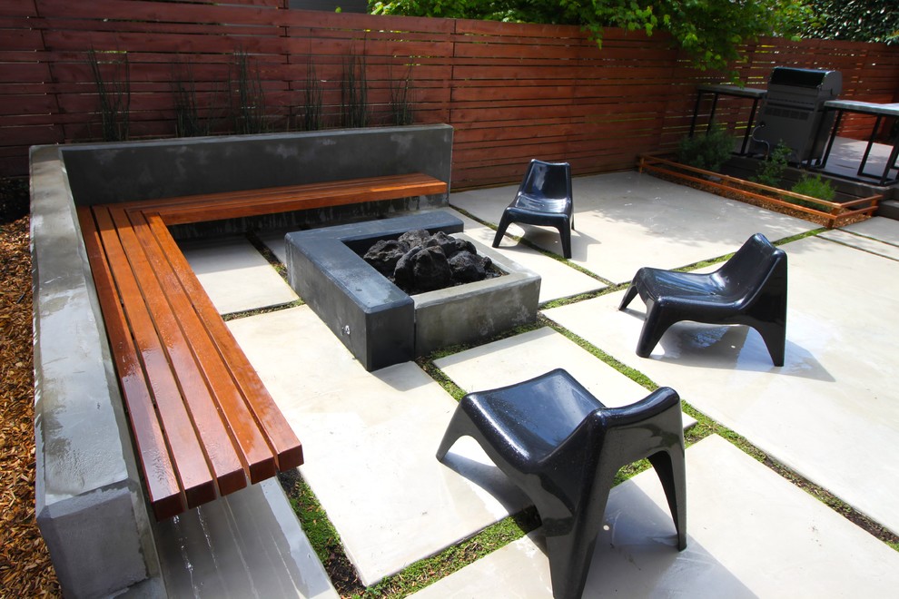 Diseño de patio minimalista de tamaño medio sin cubierta en patio trasero con brasero y suelo de hormigón estampado