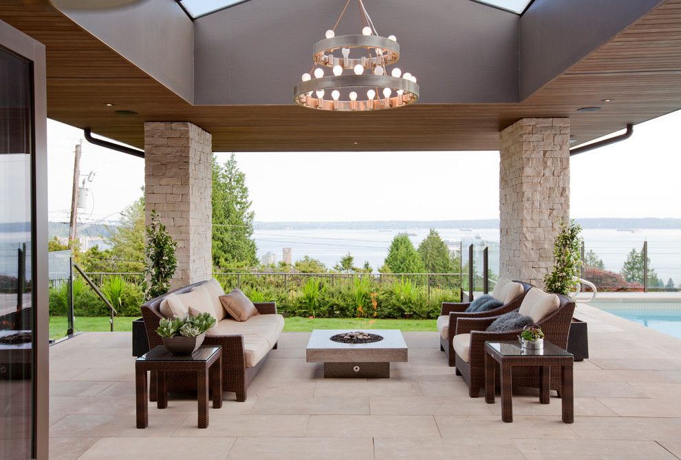 Exemple d'une terrasse arrière tendance avec un foyer extérieur, des pavés en pierre naturelle et une extension de toiture.