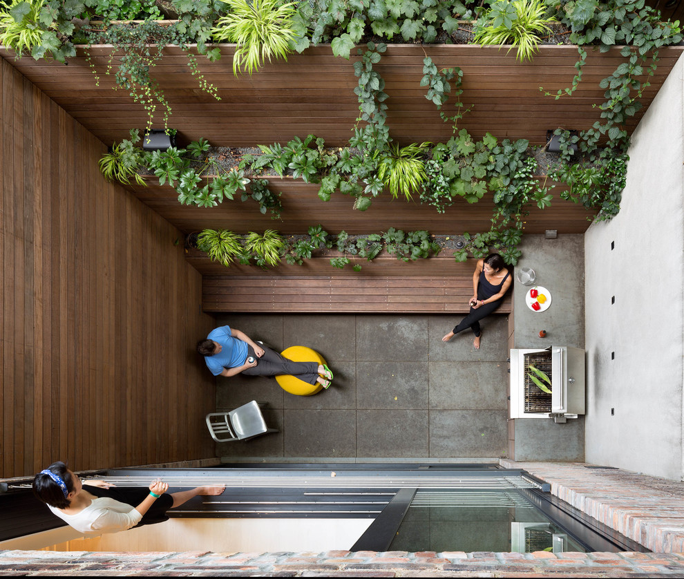 Modelo de patio actual sin cubierta en patio trasero con jardín vertical y losas de hormigón