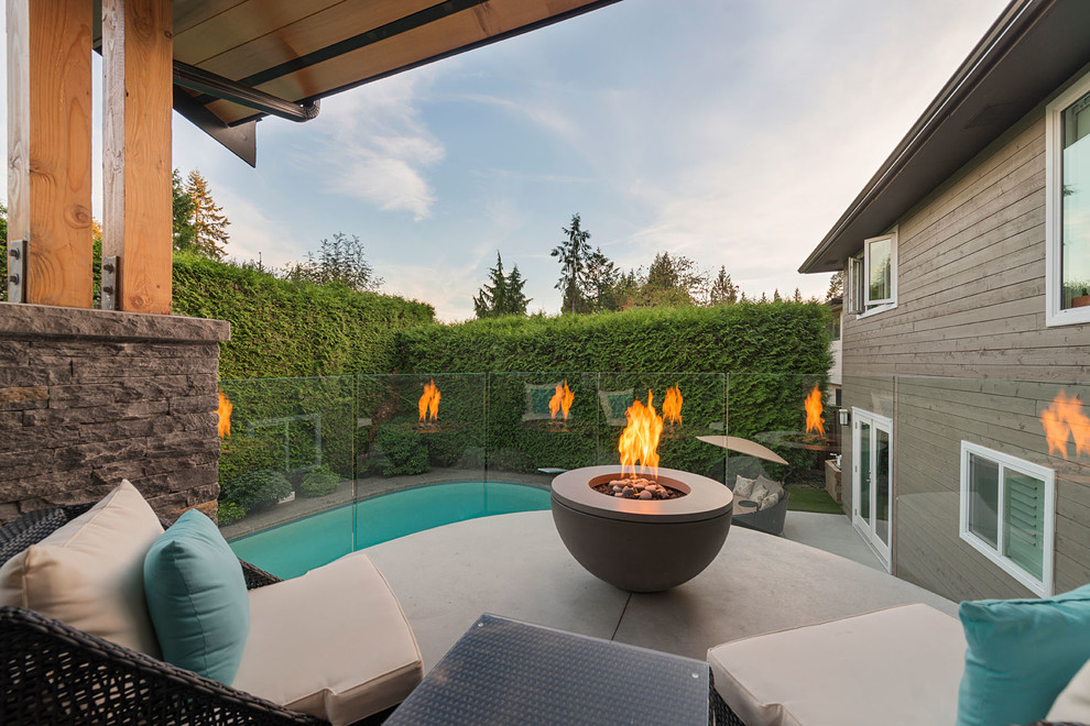 Photo of a large traditional back patio in Vancouver with a fire feature, concrete slabs and a pergola.