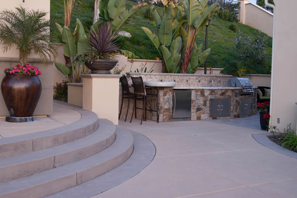 Example of a large backyard concrete paver patio kitchen design in San Diego