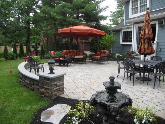 Diseño de patio clásico grande en patio trasero con fuente y adoquines de hormigón