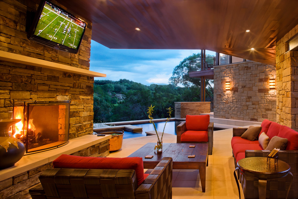 This is an example of a contemporary back patio in Austin with a fire feature and a roof extension.