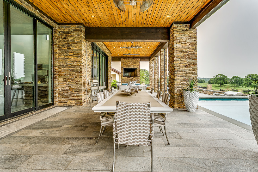 Immagine di un grande patio o portico minimalista dietro casa con piastrelle e un tetto a sbalzo