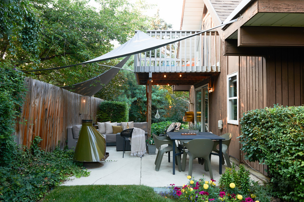 Ispirazione per un patio o portico moderno di medie dimensioni e dietro casa con un focolare, lastre di cemento e un parasole