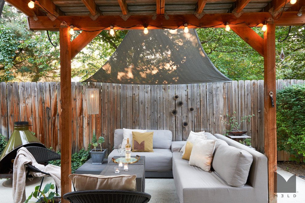 Immagine di un patio o portico moderno di medie dimensioni e dietro casa con un focolare, lastre di cemento e un parasole