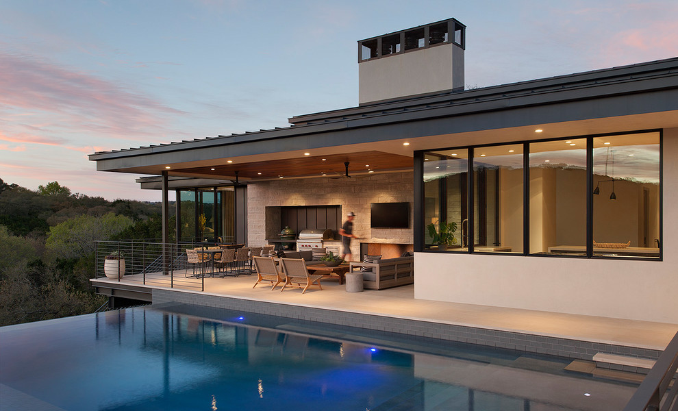 Réalisation d'une terrasse design avec une cuisine d'été et une extension de toiture.