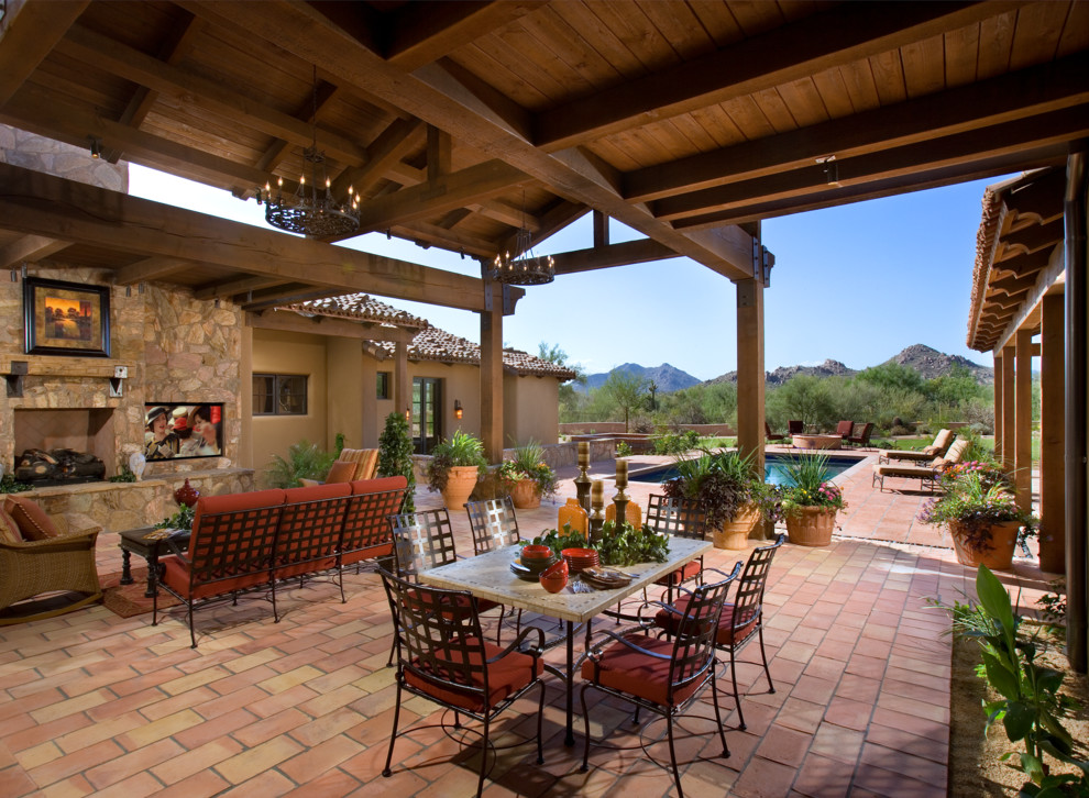 Example of a tuscan patio design in Phoenix with a fire pit and a roof extension