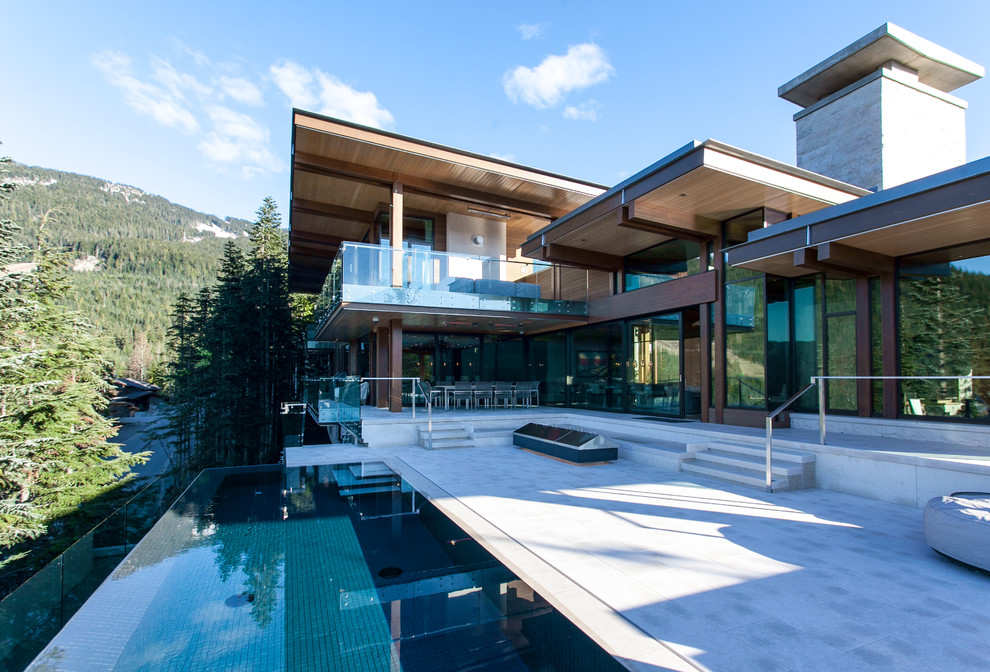 Photo of an expansive contemporary back patio in Vancouver with a water feature, stamped concrete and a roof extension.