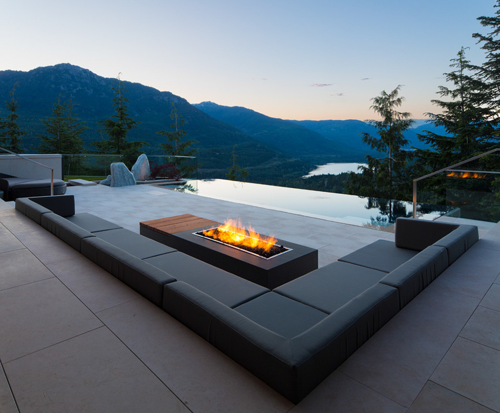 Réalisation d'une grande terrasse arrière minimaliste avec un foyer extérieur, une dalle de béton et aucune couverture.