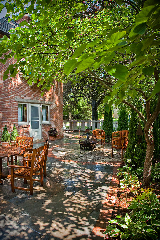 Foto di un patio o portico tradizionale dietro casa e di medie dimensioni con un focolare, pavimentazioni in pietra naturale e nessuna copertura
