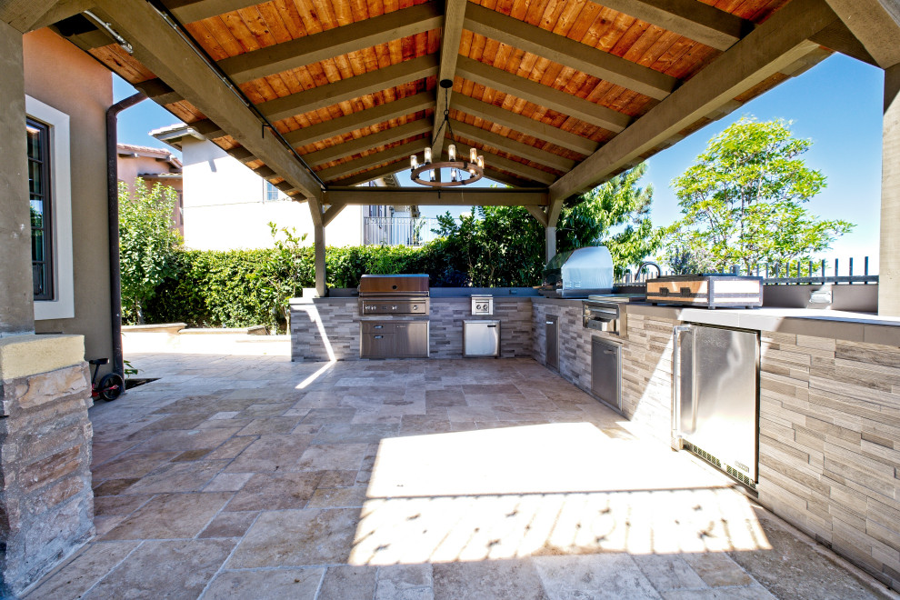 Immagine di un grande patio o portico dietro casa con pavimentazioni in pietra naturale e un tetto a sbalzo