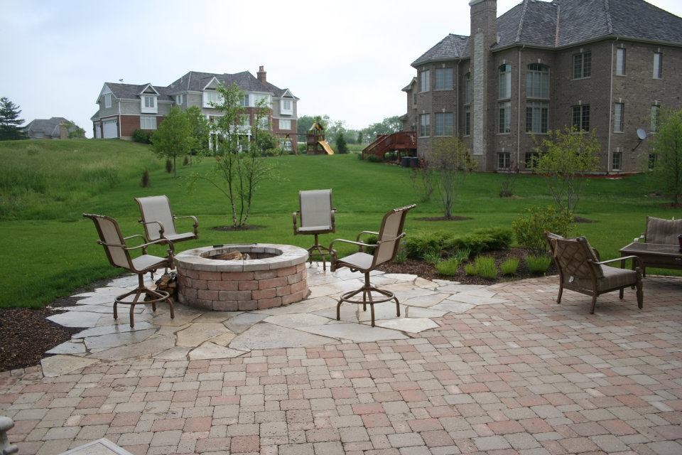 Design ideas for a large classic back patio in Chicago with a fire feature, natural stone paving and no cover.