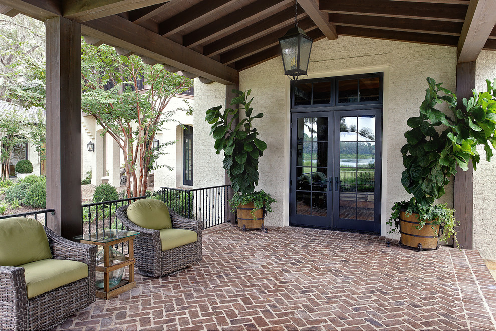 Foto di un patio o portico classico di medie dimensioni e dietro casa con pavimentazioni in mattoni e un tetto a sbalzo