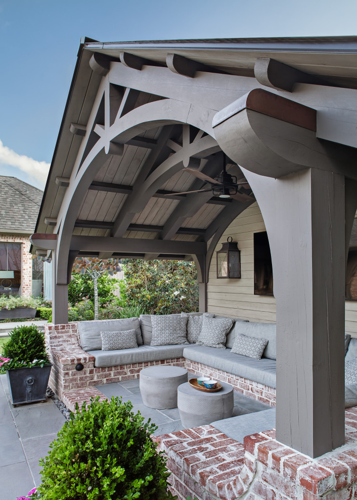 Exemple d'une terrasse arrière chic de taille moyenne avec des pavés en pierre naturelle et une extension de toiture.