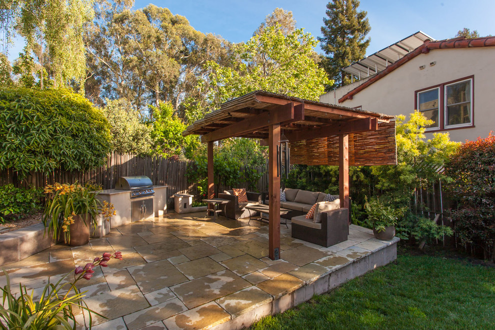 Example of a small eclectic backyard stone patio kitchen design in San Francisco with a pergola