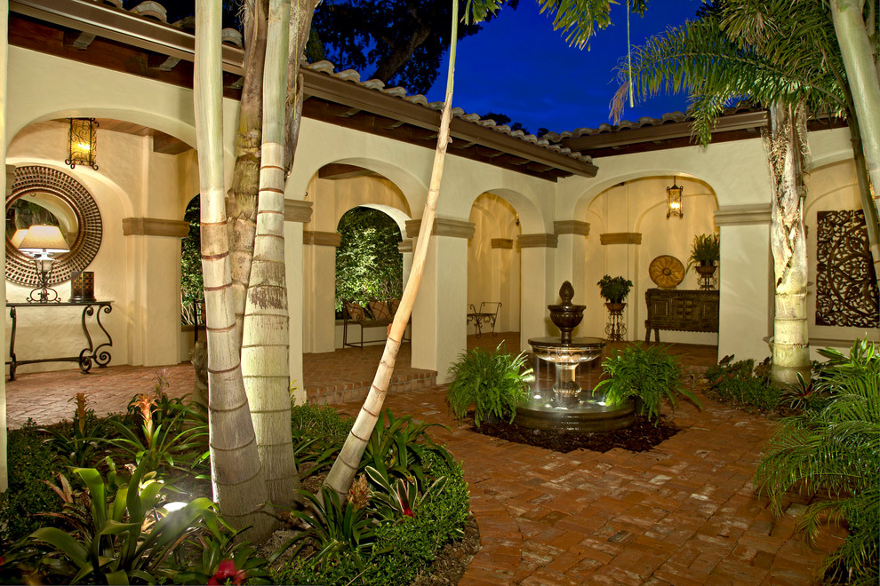 Inspiration for a mid-sized mediterranean courtyard brick patio fountain remodel in Orlando with no cover