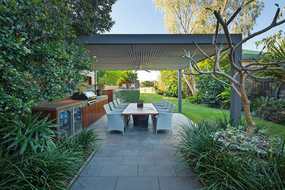 Ispirazione per un patio o portico tropicale dietro casa con pavimentazioni in cemento e una pergola