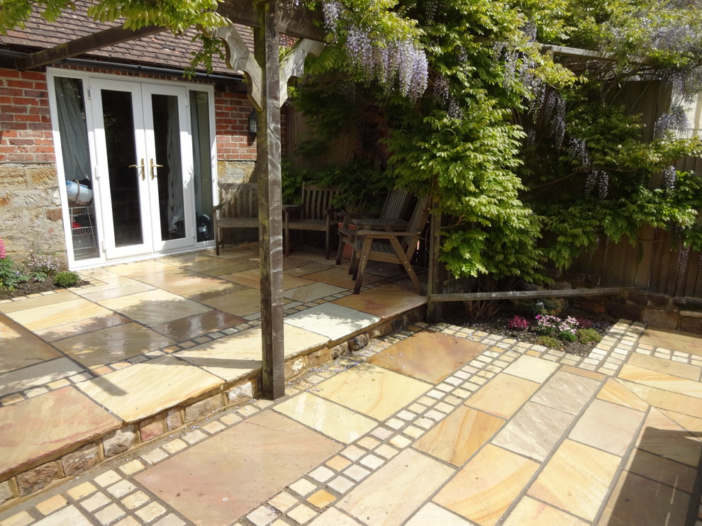 Foto de patio clásico de tamaño medio en patio trasero con adoquines de piedra natural y pérgola
