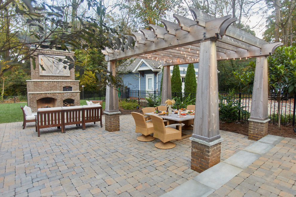 Modelo de patio clásico en patio trasero con chimenea, adoquines de ladrillo y pérgola