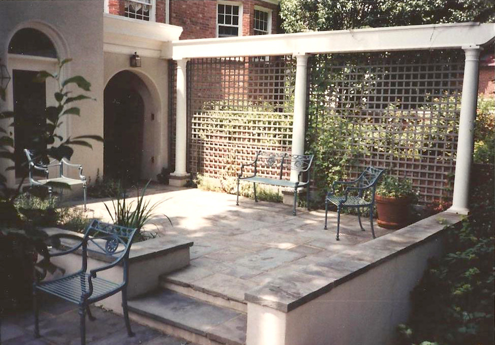 Exempel på en liten klassisk uteplats på baksidan av huset, med naturstensplattor