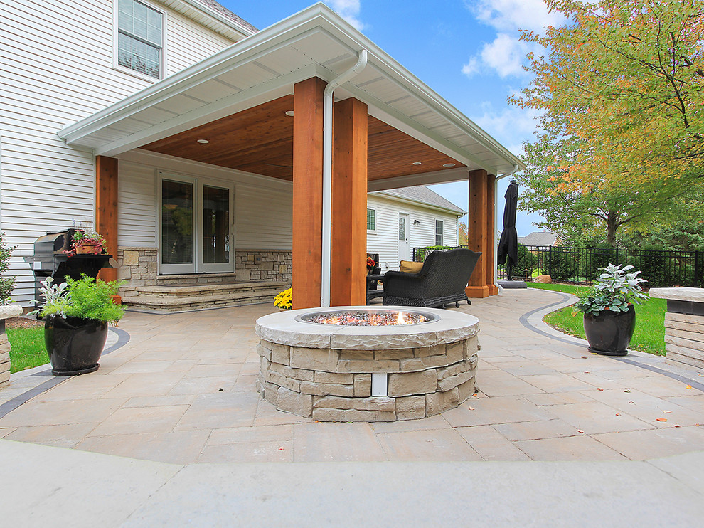 Mid-sized elegant backyard concrete paver patio photo in Chicago with a fire pit and a roof extension