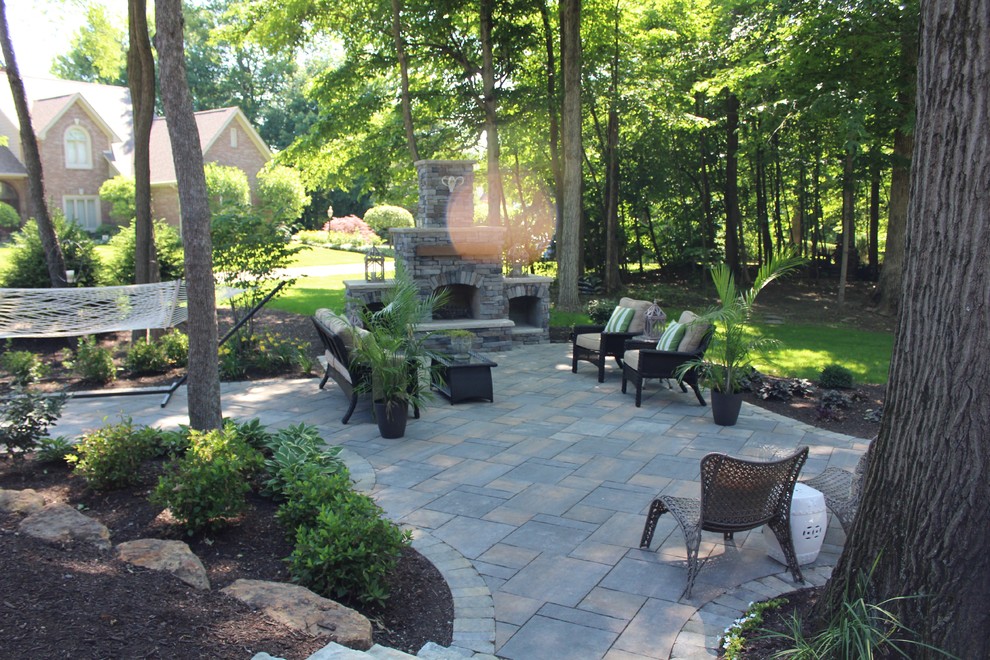 This is an example of a medium sized farmhouse back patio in Indianapolis with a fire feature and brick paving.