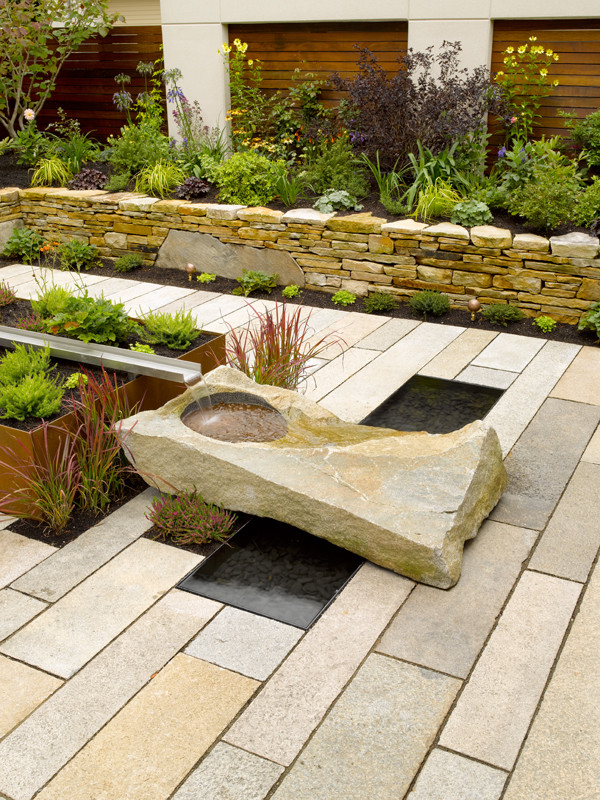 Idée de décoration pour une terrasse design avec un point d'eau et des pavés en pierre naturelle.