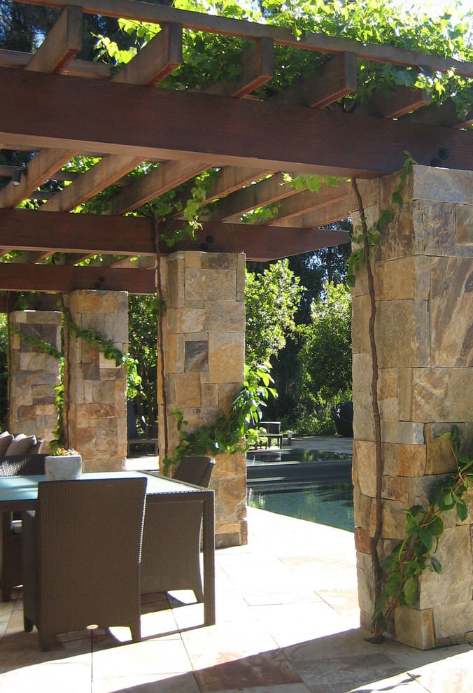 Ispirazione per un patio o portico eclettico dietro casa e di medie dimensioni con pavimentazioni in pietra naturale e una pergola